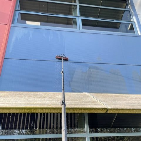 Man with long reach and wash pole for cleaning office partitions