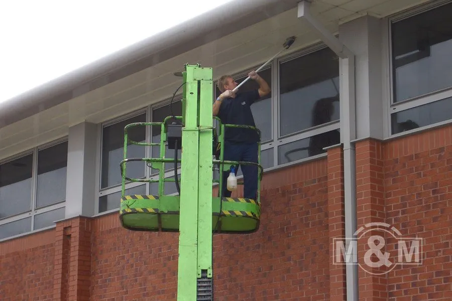 Man on cherry picker cleaning window surrounds